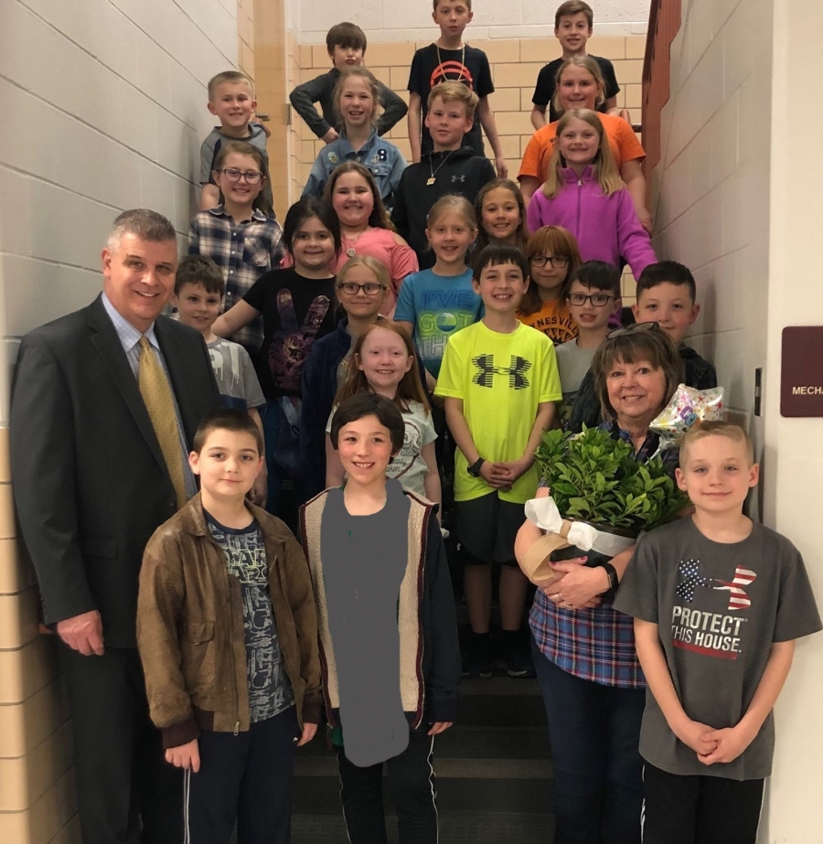 teacher holding plant and students